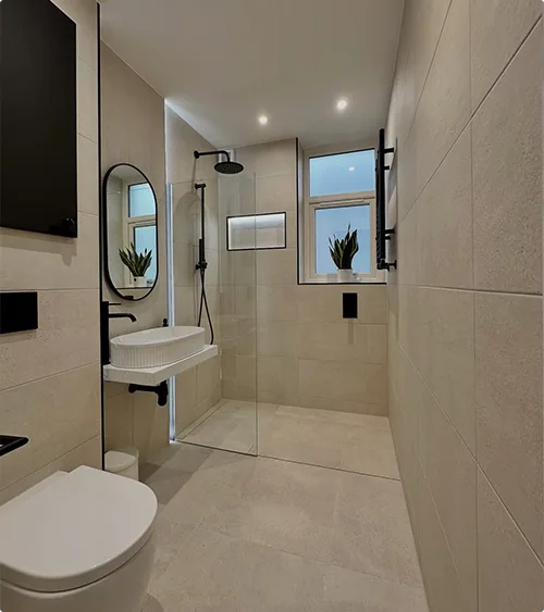 Large Stacked Beige Wall Tiles, Shower Window, Frameless Glass Panel, Oval Mirror and Minimal Floating Sink