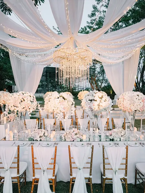 Tent-like white canopy, crystal chandelier, and tall white and blush flowers