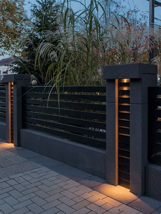 Warm Integrated Lighting in Chunky Concrete Posts beside Dark Horizontal Wood Slats