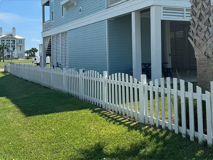 White Scalloped Picket Fence by a Coastal Blue Home