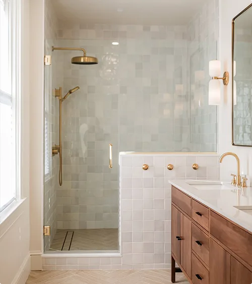 White Shower Wall Tiles in Varying Sizes, Brass Fixture, Half Wall, Toilet Area and Natural Wood Vanity