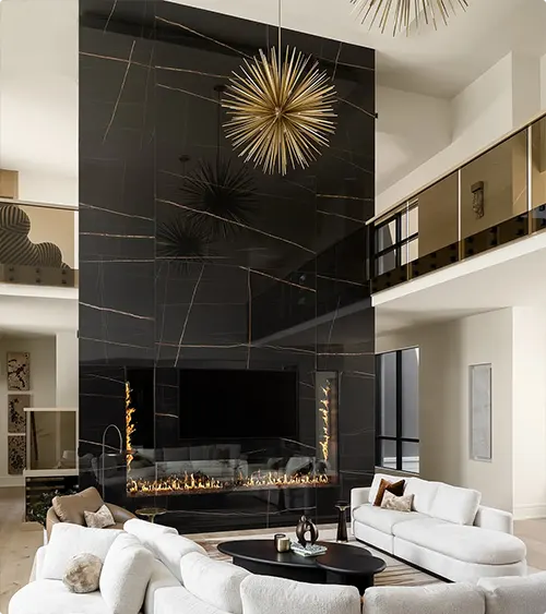 A Marble Fireplace Beneath a Gold Chandelier in a Two-Story Design