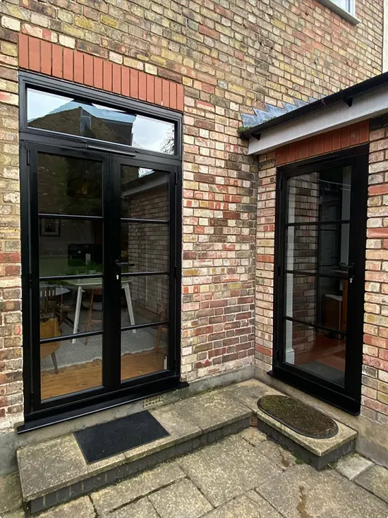 Brick Cottage Exterior with Two Black French Doors