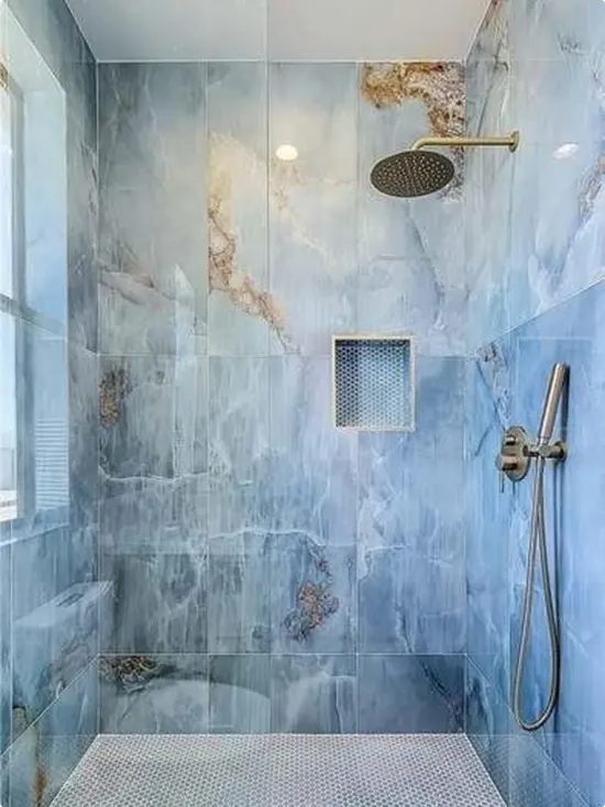 Shower with blue marble tile, penny tile floor, and gold rain head
