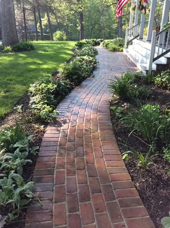 Brick Path Curving Toward a White Wraparound Porch