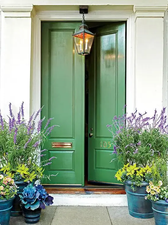 Double front door in forest green beside lantern light