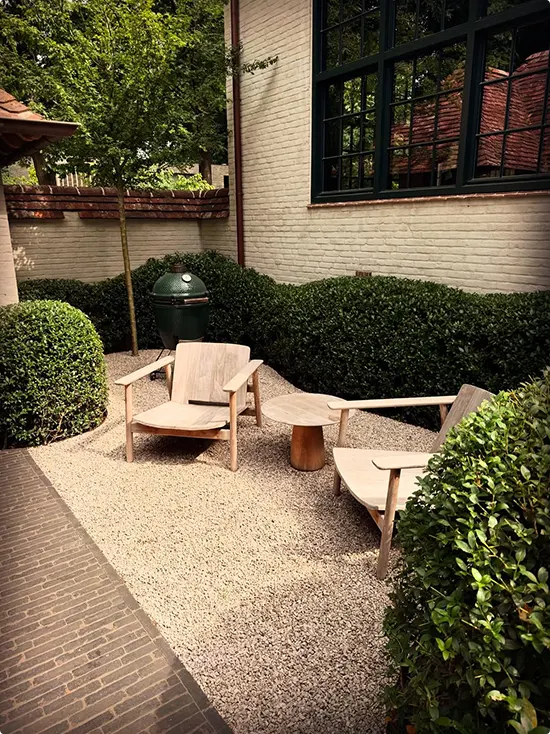 Big Green Egg on gravel by clipped hedges