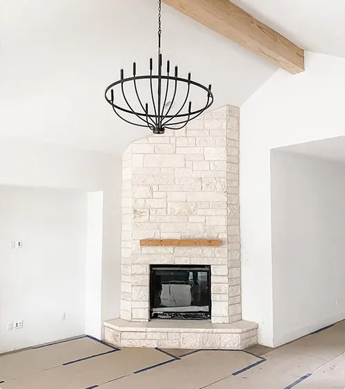 Whitewashed Brick Fireplace with Raw Wood Mantel and Chandelier