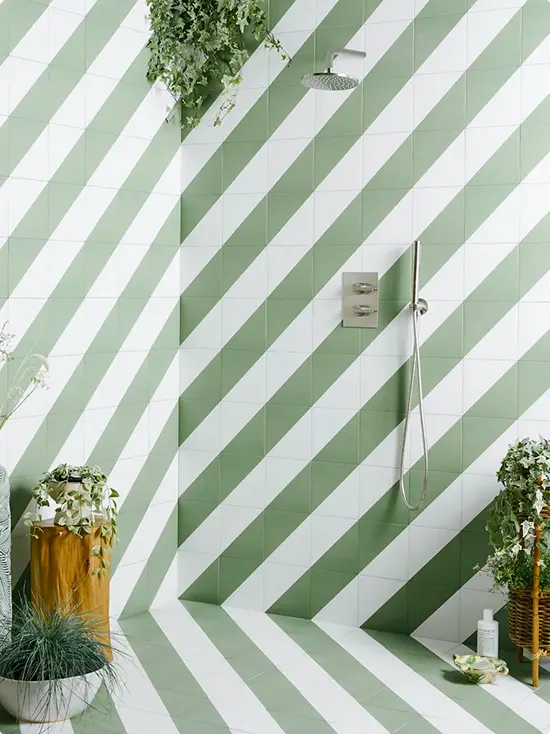 Floor to ceiling green and white diagonal shower tile with a hanging trailing plant