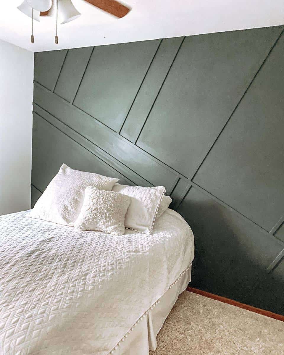 accent-wall-green-bedroom-ideas-malloryrankin Cozy bedroom with a white bedspread and pillows, set against a dark green geometric accent wall