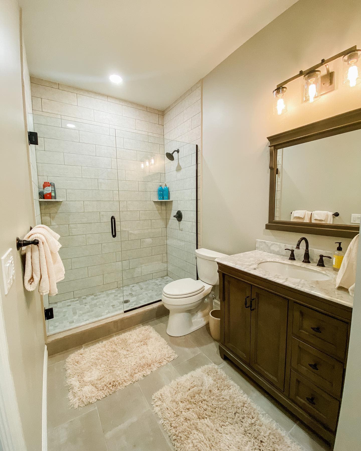 bathroom20basement20apartment20ideas20-majestichomesolutions Simple modern bathroom with glass shower, wooden vanity, and beige tile flooring.