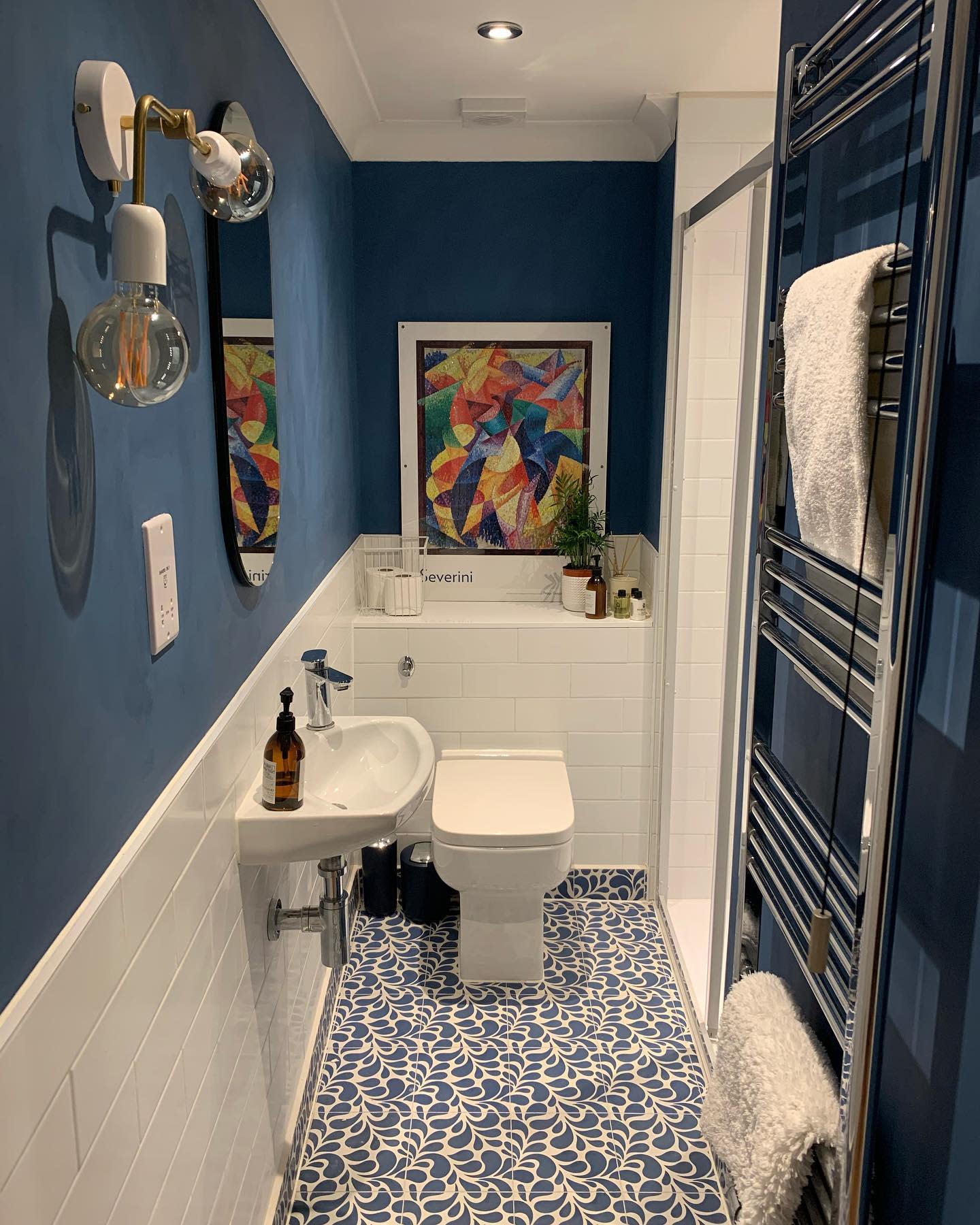 bathroom20basement20apartment20ideas20-thisoldtownhouse Modern blue bathroom with abstract art, patterned floor tiles, and wall-mounted towel rail.