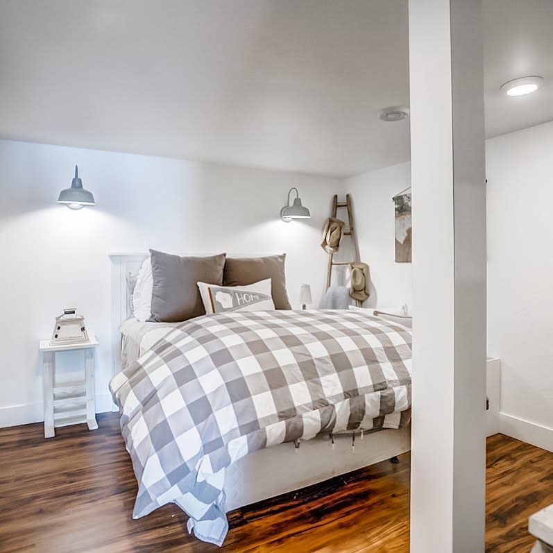 bedroom20basement20apartment20ideas20-ashleykix White bedroom with plaid bedding, timber floors, and rustic ladder decor.