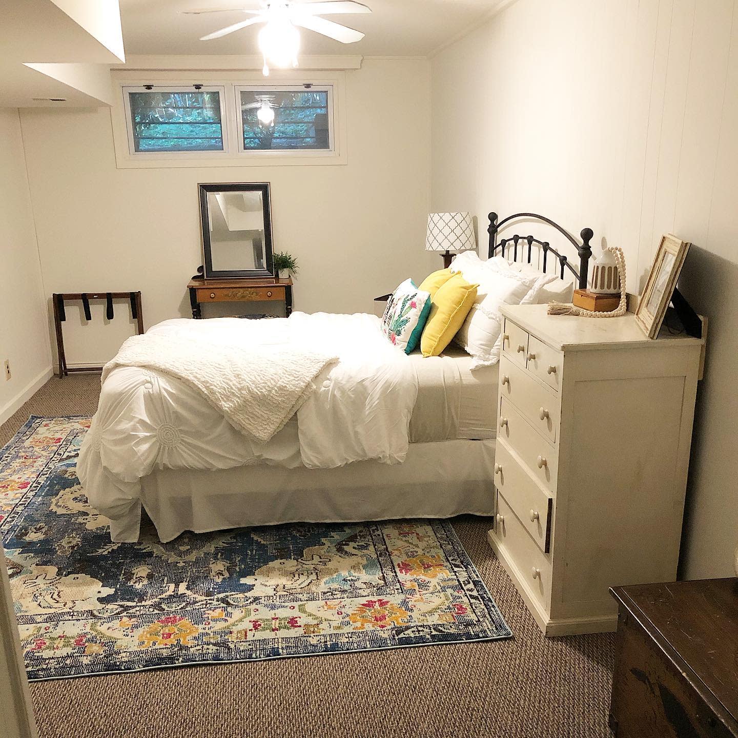 bedroom20basement20apartment20ideas20-my_chevychase__home Small cozy bedroom with colorful rug, white bedding, and wooden dresser.