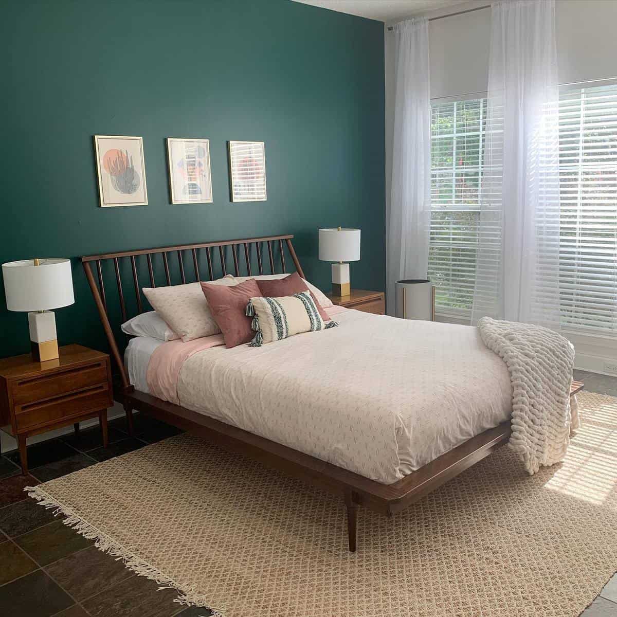 classic-green-bedroom-ideas-ervargo Cozy bedroom with a wooden bed, white bedding, green accent wall, and large windows letting in natural light