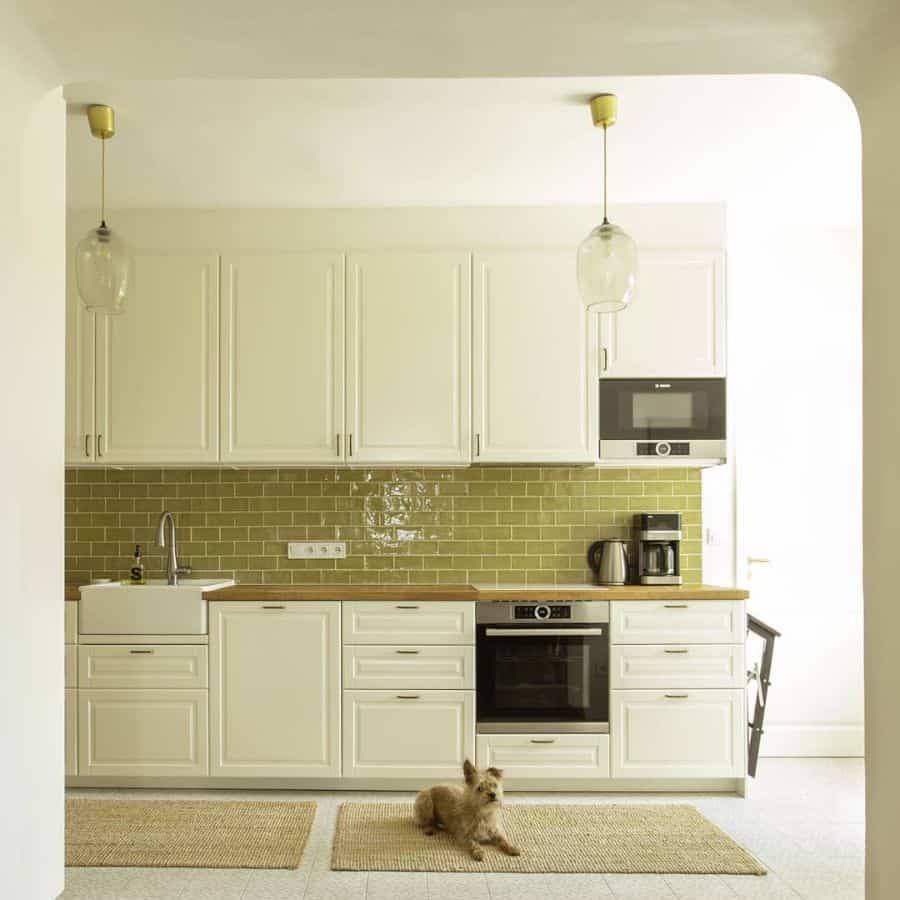 large open kitchen with white cabinets and green subway tile splashback