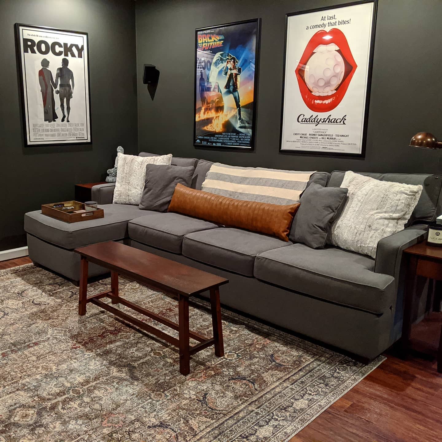 decoration20basement20apartment20ideas20-homeonportsmouth Lounge room with gray sofa, movie poster wall art, and patterned rug.