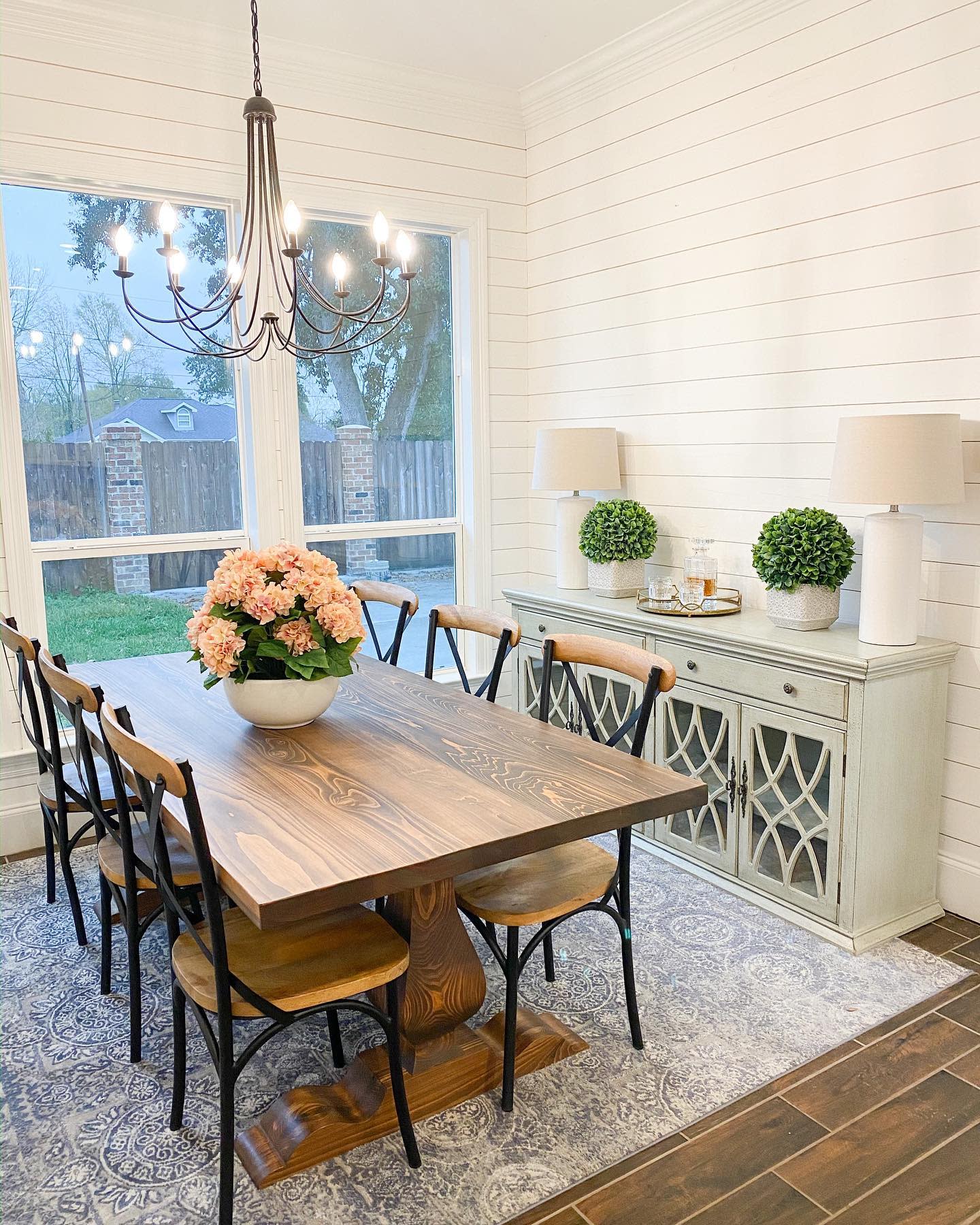 white panel dining room cabinet wood table flower arrangement chandelier