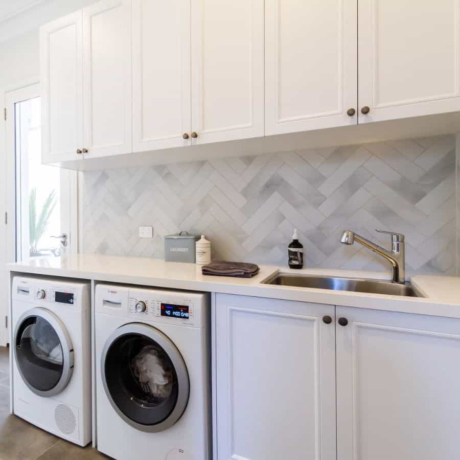 faucet-laundry-room-sink-ideas-thekitchendesigncentre white cabinet subway tile backsplash laundry washer and dryer