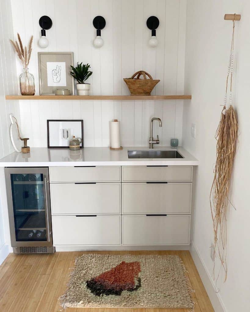white shiplap feature wall in small kitchen with gray cabinets and wood wall shelf