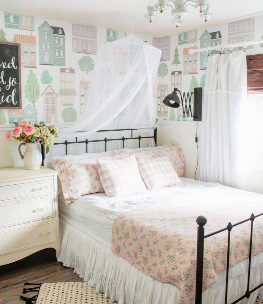 Kids' bedroom with house-pattern wallpaper, floral bedding, and white vintage dresser.