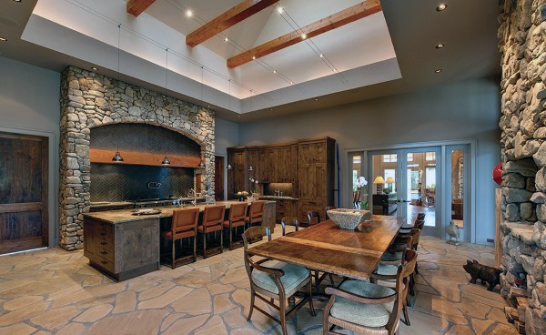 stone kitchen with wood cabinets and large dining table and chairs