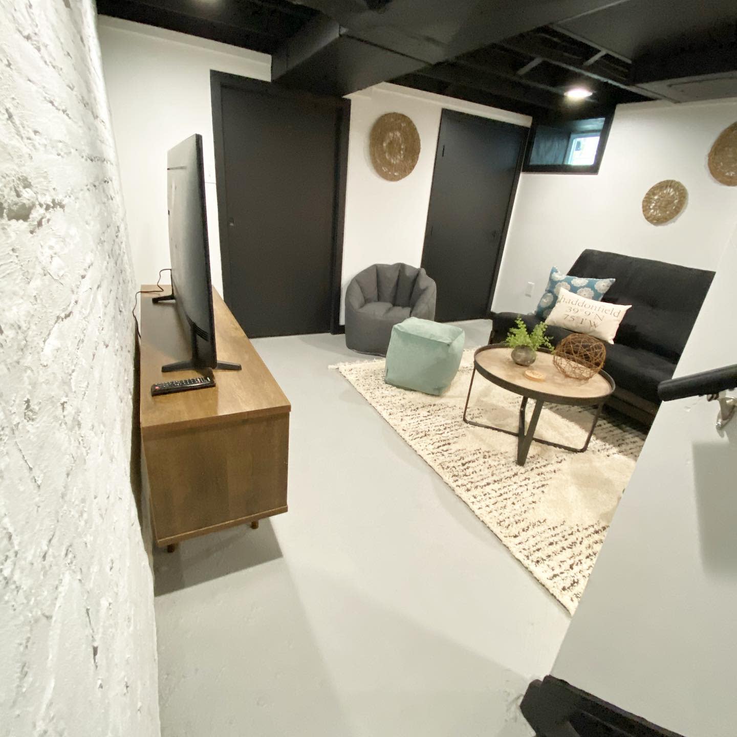 living20room20basement20apartment20ideas20-meant_to_bee_home Small basement living room with black futon, TV, and neutral decor accents.