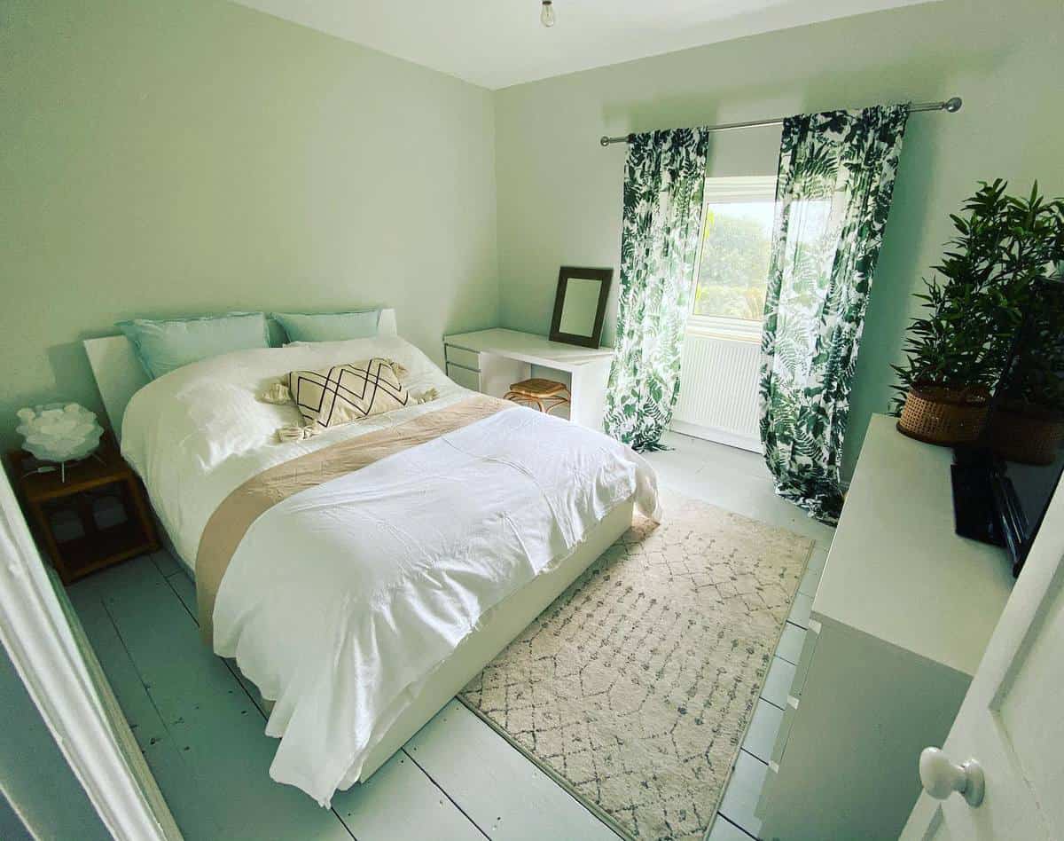 master-green-bedroom-ideas-bring_the_sunshine_home Cozy bedroom with a white bed, patterned curtains, a rug, and plants near a window