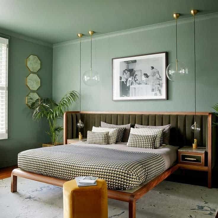 master-green-bedroom-ideas-home-818 Stylish bedroom with green walls, patterned bedding, hanging lights, plants, and framed art above the bed