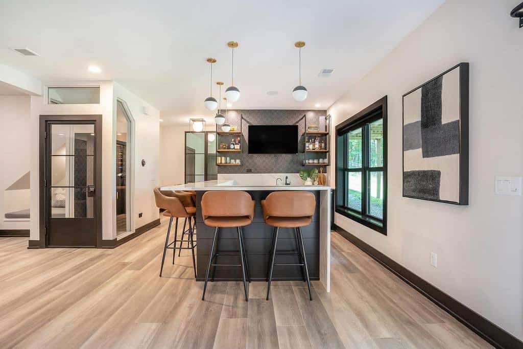 modern-basement-bar-ideas-kristiekoningdesign Modern basement bar with sleek black cabinetry, leather stools, and geometric wall art.