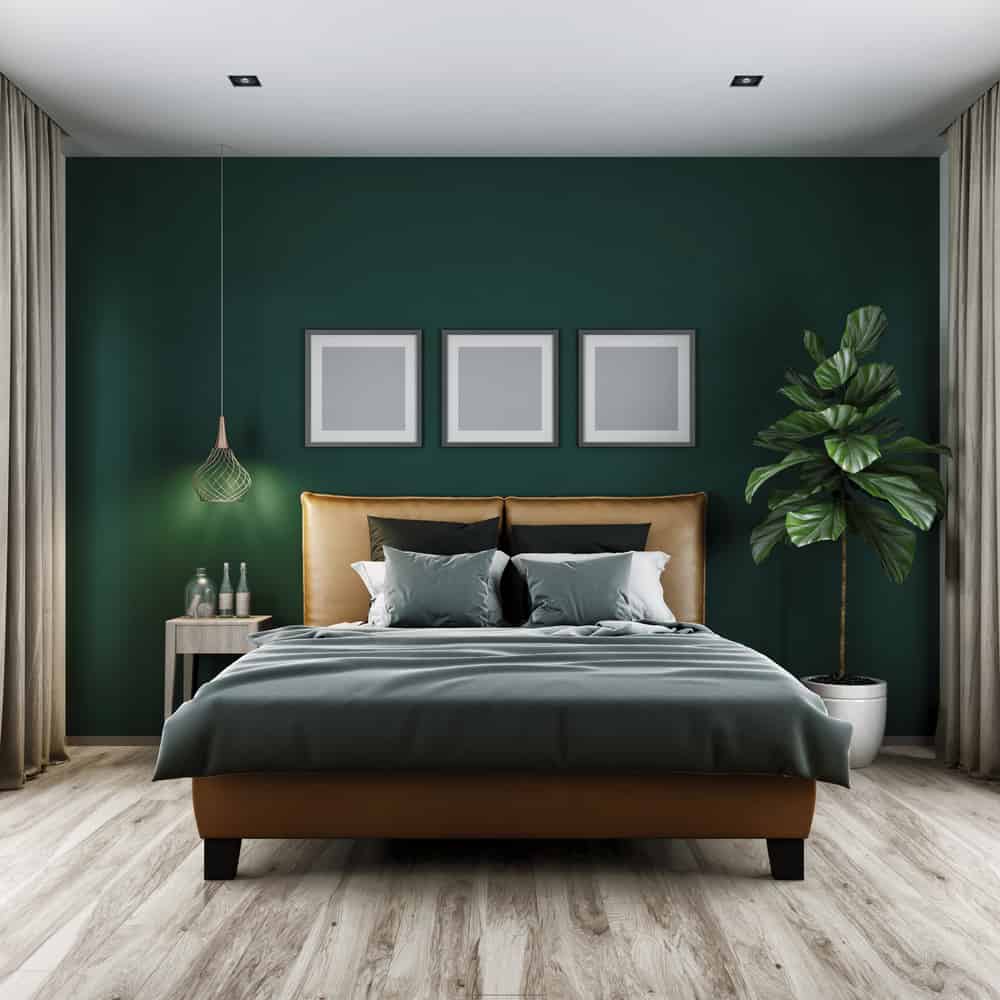 modern-green-bedroom-ideas-1-1 Modern bedroom with green walls, framed art, pendant light, potted plant, and a bed with gray and beige bedding