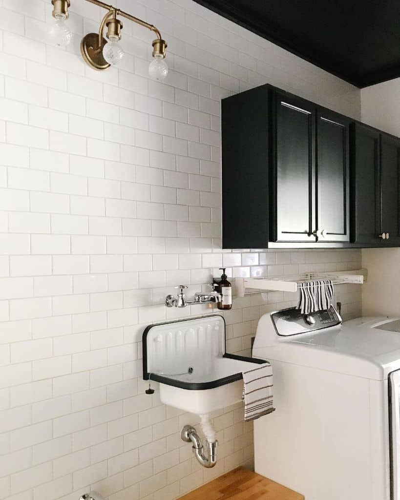 narrow-laundry-room-sink-ideas-dewitt17designandbuild white tile wall laundry sink and black cabinets