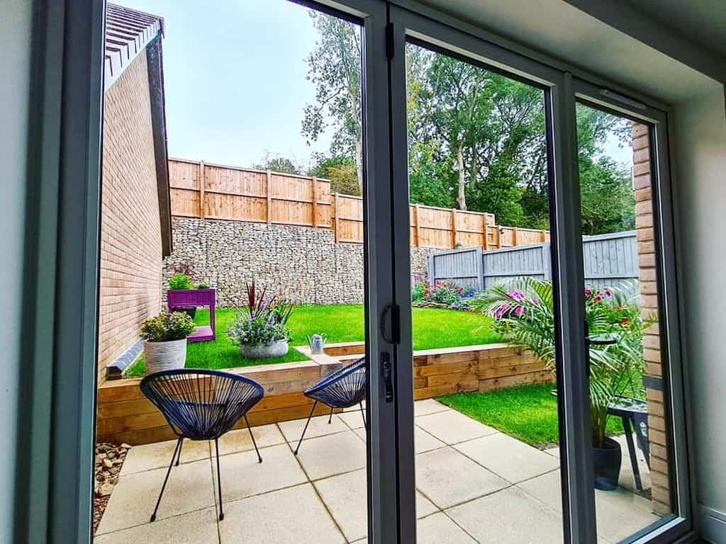 raised garden wood retaining wall square pavers wicker chairs