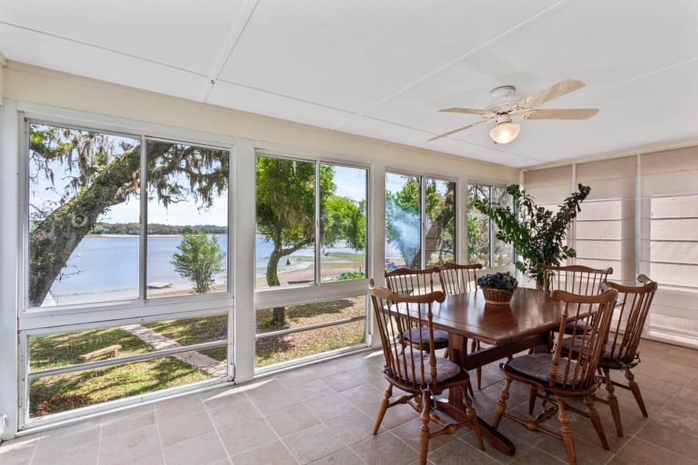 rustic-enclosed-patio-ideas-2 rustic enclosed patio wood dining table and chairs tile floor ceiling fan and light