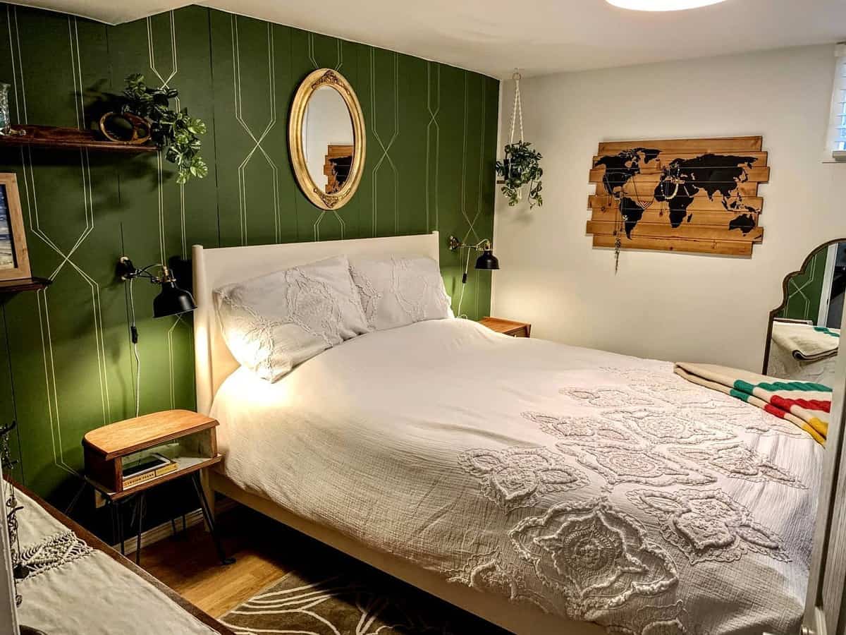 rustic-green-bedroom-ideas-emcostello Cozy bedroom with a green accent wall, white bed, round mirror, and a world map decor piece