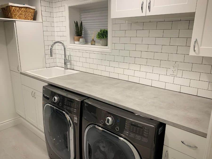 sink-cabinet-laundry-room-sink-ideas-refreshhomeimprovements white tile white laundry black washer and dryer