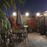 small concrete patio with black ornate table and chairs