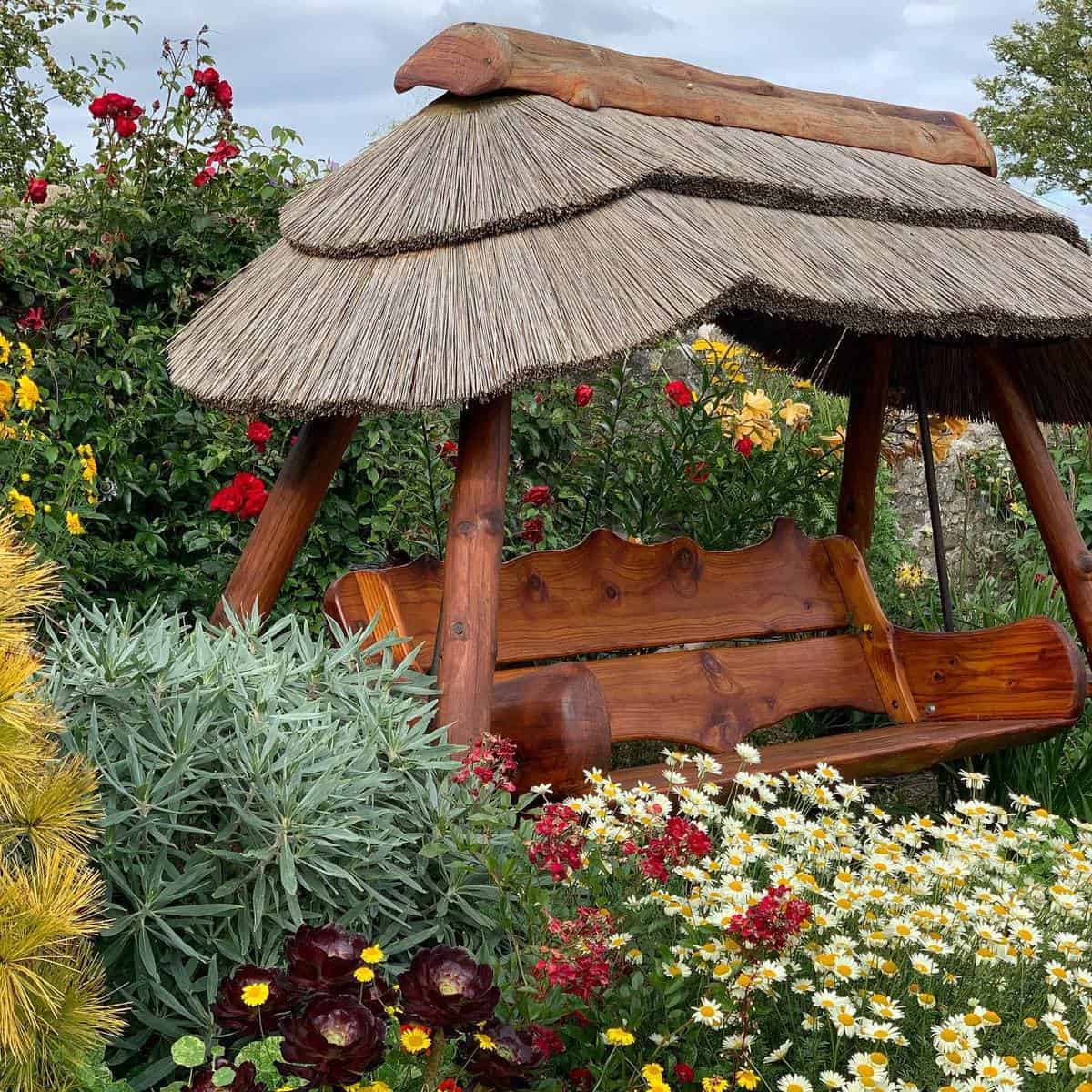 swing-bench-garden-bench-ideas-thorntonhallgardens backyard stained wood swing bench with roof
