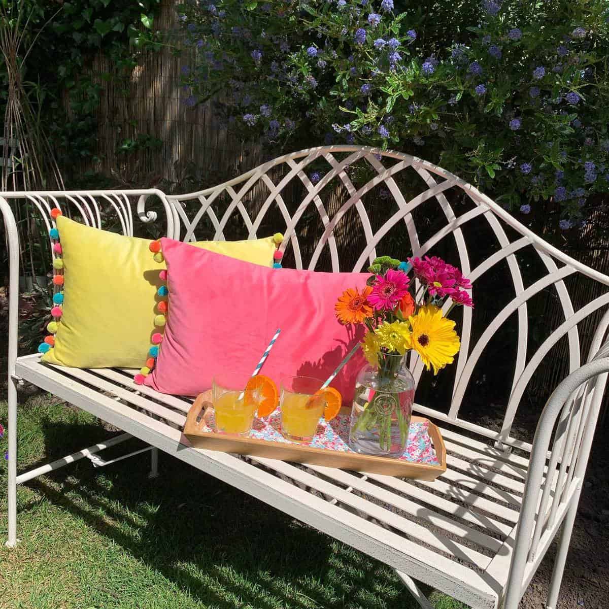 wrought-iron-garden-bench-ideas-selfraising_flowers white wrought iron garden bench pink and yellow cushions