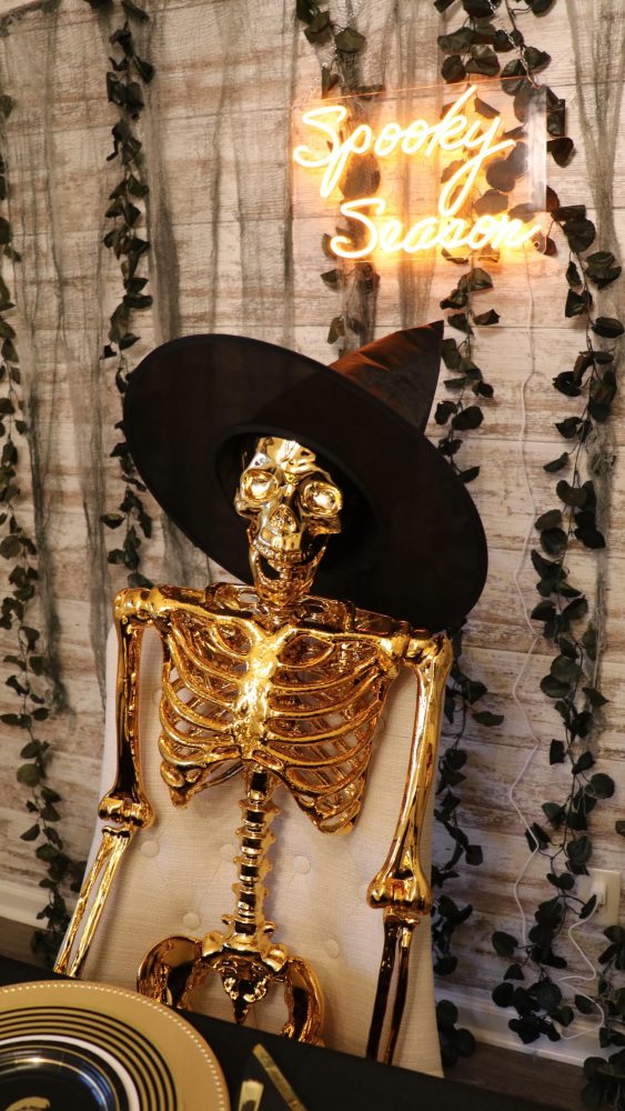 Gold Skeleton in a Witch Hat by a Neon Sign