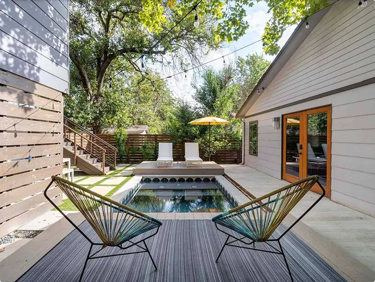 Mid-Century Pool Design with Retro Energy, a Plunge Pool, Scalloped Tile, Two Woven Acapulco Chairs, and Crisscrossed Overhead String Lights