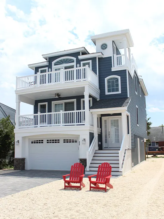 Red Adirondack Chairs at the Front of a Navy-Gray Beach House