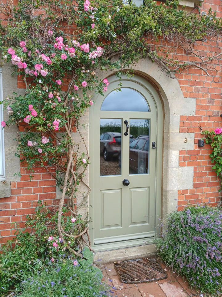 Sage Green Arched Door Against Traditional Red Brick
