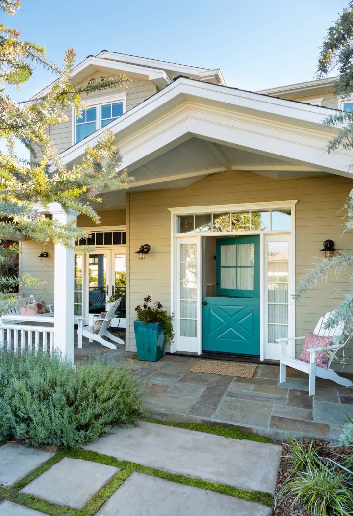 A Craftsman porch with two teal Dutch doors in the French style